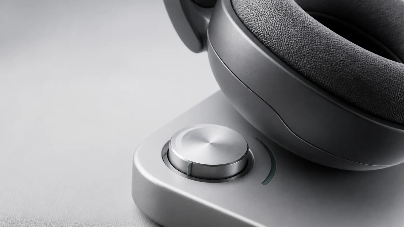 Close view of a headphone cushion beside a restrained silver volume control